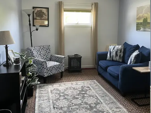 A comfortable sofa and chair are pictured in a cozy office setting