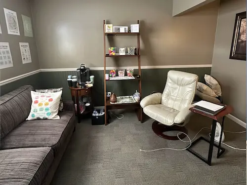 A relaxed office space & group counseling room with leather chairs and artwork is shown